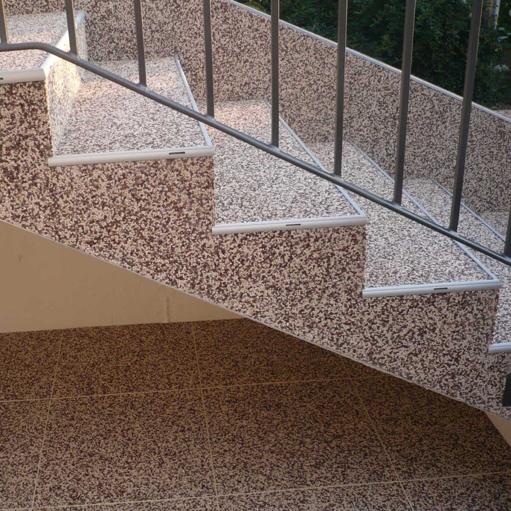 Freistehende Treppe mit Steinteppich belegt.
