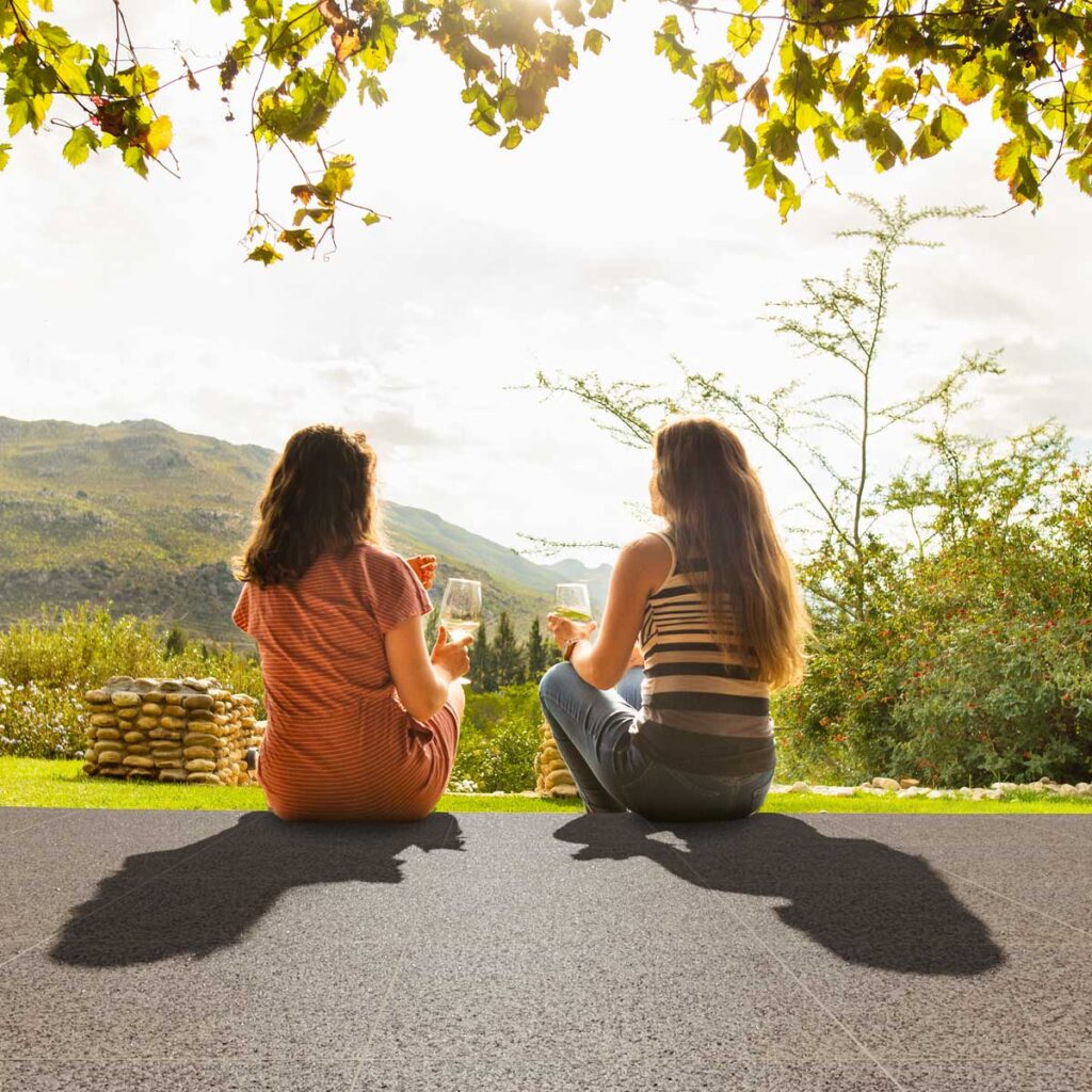 Zwei Frauen sitzen auf dem Steinteppich-Boden und genießen den Feierabend